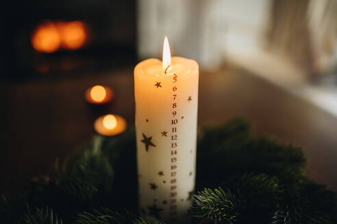 Nahaufnahme einer brennenden Weihnachtskerze im Kranz. Weihnachtskerze mit Dezember-Monatszahlen. - JLPSF10921