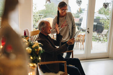 Ein älteres Ehepaar benutzt ein digitales Tablet für einen Videogespräch mit der Familie an einem Weihnachtstag. Ein älterer Mann und eine Frau führen ein Videogespräch. - JLPSF10927