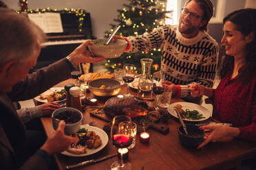 Familie beim gemeinsamen Abendessen am Weihnachtsabend in ihrem Haus. Europäische Familie beim Abendessen am Weihnachtsabend. - JLPSF10958