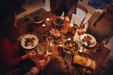 Top view of dining table during Christmas dinner at scandinavian home. Senior man serving roasted turkey to family. - JLPSF10963