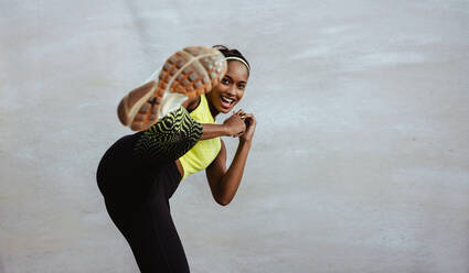 African woman in fitness outfit doing kick boxing workout. Athlete woman doing leg exercise against white background. - JLPSF11017