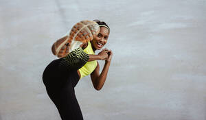 Afrikanische Frau in Fitness-Outfit macht Kickboxen Workout. Athleten Frau tut Bein Übung gegen weißen Hintergrund. - JLPSF11017