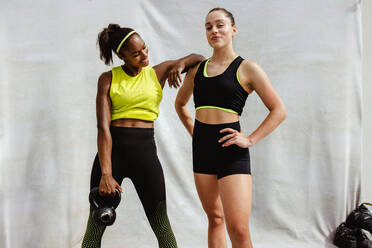 Athlete women wearing sports clothing with kettle bell standing on white background. Female with her personal trainer after workout session. - JLPSF11068