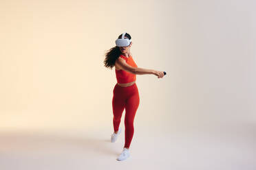 Junge Frau, die mit 3D-Technologie trainiert. Sportliche junge Frau, die ein Virtual-Reality-Fitnessspiel erkundet. Sportliche junge Frau mit Virtual-Reality-Brille in einem Studio. - JLPSF11091
