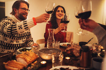 Eine glückliche Familie stößt mit Wein an und genießt das Abendessen an Heiligabend. Familie beim gemeinsamen Abendessen an Heiligabend. - JLPSF11131