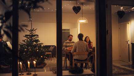 Familie beim gemeinsamen Weihnachtsabendessen in ihrem Haus. Europäische Familie beim Abendessen am Weihnachtsabend in einem schön dekorierten Haus; - JLPSF11133