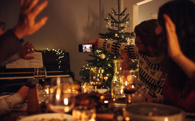Ein Mann macht ein Selfie mit seiner Familie während des Weihnachtsabendessens. Die Familie posiert für ein Selfie während des Weihnachtsessens. - JLPSF11136