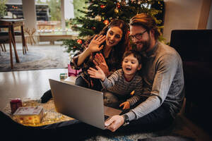 Eine europäische Familie begrüßt ihre Freunde per Videoanruf an einem Weihnachtstag. Soziale Distanzierung der Familie an Weihnachten. - JLPSF11143