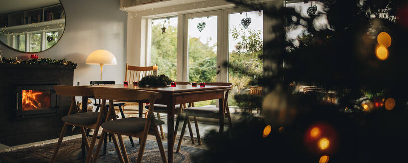 Innenaufnahme eines für den Weihnachtsabend geschmückten Familienhauses: Esstisch am Kamin mit Weihnachtsbaum. - JLPSF11146