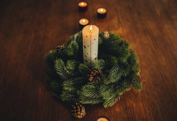 Draufsicht auf Weihnachtsdekoration auf Holztisch, Adventskranz mit brennenden Kerzen. - JLPSF11148