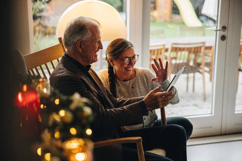 Familie mit einem Videoanruf auf dem Tisch PC während Weihnachten. Älteres Paar begrüßt Familie während eines Videoanrufs an einem Weihnachtsabend. - JLPSF11150