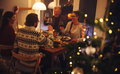 Europäische Familie stößt mit Wein an und genießt das Abendessen am Heiligabend. Familie der zweiten Generation beim gemeinsamen Abendessen am Heiligabend. - JLPSF11166