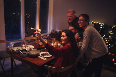 Familie macht Selfies am Weihnachtstisch. Frau klickt Selfie-Porträt mit Familie am Weihnachtsabend zu Hause. - JLPSF11170