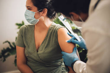 Doctor prepping a womans arm with alcohol swop. Female getting her arm disinfected for her covid vaccine. - JLPSF11218