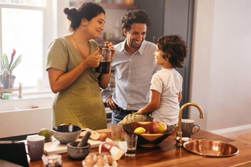 Zwei liebevolle Eltern verbringen einige Zeit mit ihrem Sohn in der Küche. Mama und Papa lächelnd im Gespräch mit ihrem Sohn beim Frühstück Zeit. Happy ethnischen Familie Bonding zu Hause. - JLPSF11277