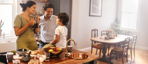 Ethnic parents spending some quality time with their son in the kitchen. Mom and dad smiling while talking to their son at breakfast time. Happy young family bonding at home. - JLPSF11278