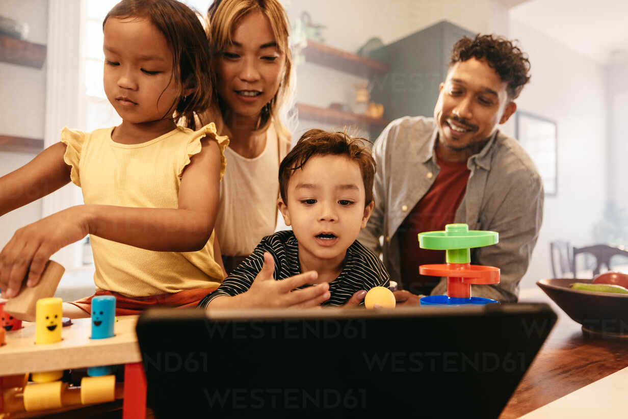 Young boy speaking expressively on a video call. Happy family of four  communicating with their loved ones using a digital tablet. Two parents  spending time with their children at home. stock photo