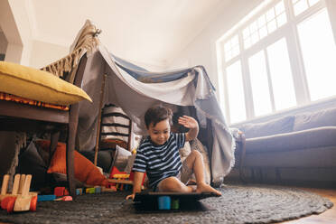 Sweet little boy watching a kids programme on a digital tablet. Adorable young boy raising his hands while looking at education content online. Little boy sitting alone in his play area. - JLPSF11316