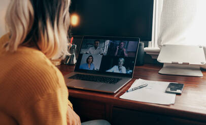 Businesswoman attending a virtual meeting while working in her home office. Female entrepreneur using a laptop to video call her business partners while working remotely. - JLPSF11361