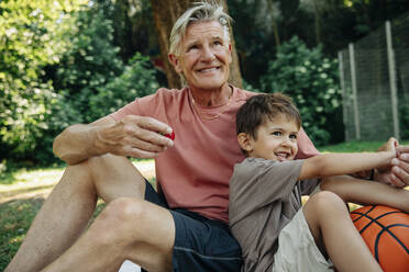 Happy boy enjoying with grandfather during picnic at park - MASF32051