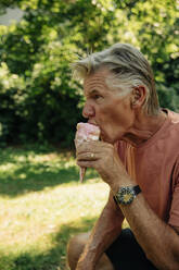 Senior man eating ice cream at park - MASF32056