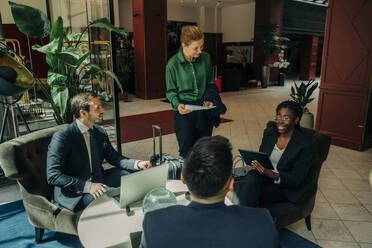 Junge Geschäftsfrau bespricht Strategie mit männlichen und weiblichen Fachleuten in einer Hotellounge - MASF32171