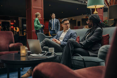 Männliche und weibliche Unternehmer diskutieren in einer Hotellounge über Geschäftsstrategien - MASF32190