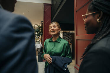 Smiling mature businesswoman talking with male and female colleagues in hotel - MASF32194