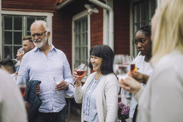 Happy woman holding wineglass with family during social gathering - MASF32214