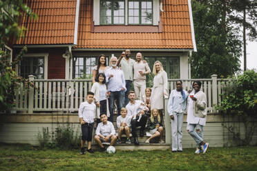 Mehrgenerationenfamilie mit Weinglas posiert auf der Veranda vor dem Haus - MASF32219