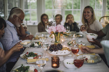Mehrgenerationen-Familie genießt das Abendessen auf dem Tisch während einer Party zu Hause - MASF32236