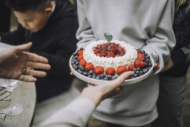 Mittelteil eines Jungen, der einer Frau frischen Kuchen zum Geburtstag schenkt - MASF32273