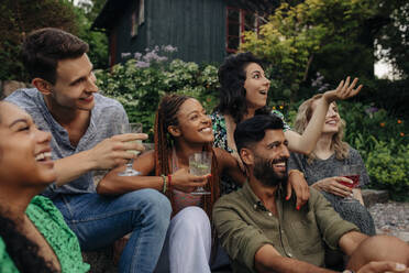 Happy male and female friends with drinks having fun at garden party - MASF32310