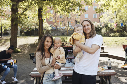 Porträt von lächelnden Eltern, die ihre Töchter in den Kindergarten tragen - MASF32347