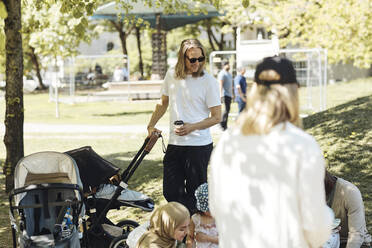 Mann mit Kinderwagen im Gespräch mit Freunden im Park - MASF32358