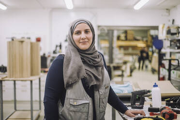 Porträt einer lächelnden Schreinerin mit Kopftuch in einer Werkstatt - MASF32433