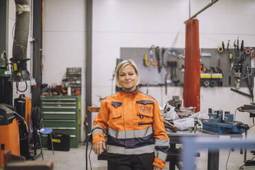 Portrait of smiling carpenter in reflective clothing standing in workshop - MASF32443