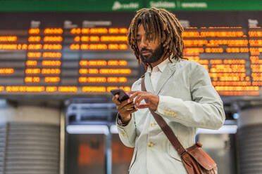 Geschäftsmann benutzt Smartphone am Hauptbahnhof - DLTSF03130