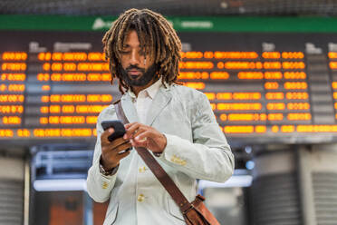 Businessman using mobile phone at central station - DLTSF03131