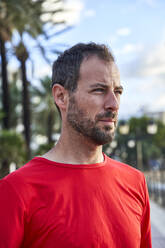 Man wearing red t-shirt on footpath - VEGF06061