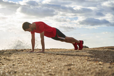 Mann macht Liegestütze auf Sand an einem sonnigen Tag - VEGF06070