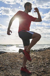 Dedicated man exercising at beach on sunny day - VEGF06081