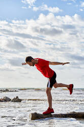 Man balancing on wood log over sea - VEGF06082