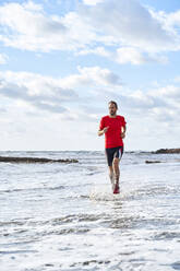 Man running on coastline at beach - VEGF06083