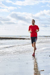 Man running at beach on sunny day - VEGF06084