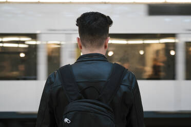 Junger Mann mit Rucksack am Bahnhof - EGAF02575