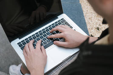 Hands of young student using laptop on wall - EGAF02583