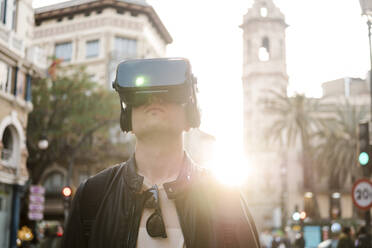 Mann trägt Virtual-Reality-Simulator in der Stadt an einem sonnigen Tag - EGAF02587