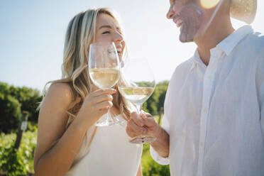 Glückliches Paar stößt an einem sonnigen Tag in einer Weinkellerei auf den Wein an - MDOF00016