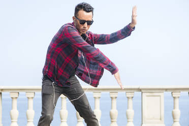 Man wearing sunglasses dancing in front of railing - ACTF00279